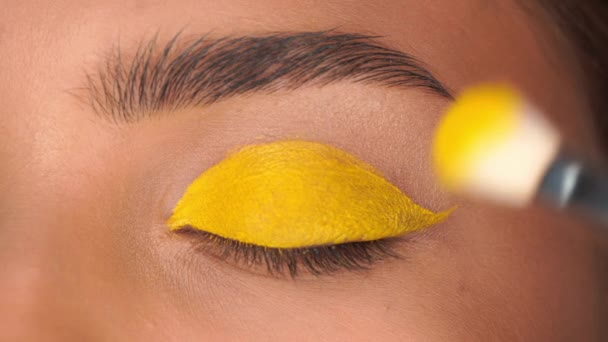 vue recadrée de la femme appliquant ombre à paupières jaune avec pinceau cosmétique - Séquence, vidéo