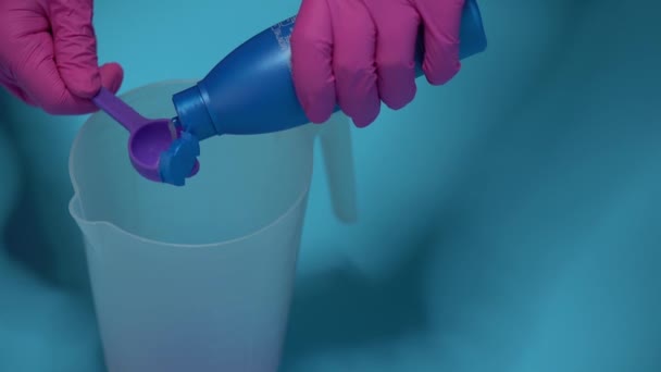 vista ritagliata della persona che versa il liquido nel cucchiaio dosatore sul blu - Filmati, video