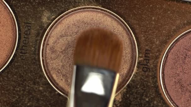 vista superior del cepillo cosmético cerca de sombra de ojos marrón con letras glam - Imágenes, Vídeo
