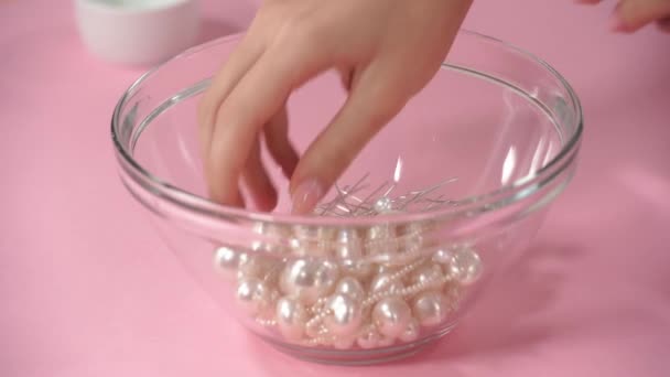 vue recadrée de la femme prenant des épingles à cheveux avec des perles blanches sur rose - Séquence, vidéo