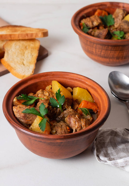Goulash, beef stew with vegetables and thyme in pots with onion and greens. Irish stew. - Photo, Image