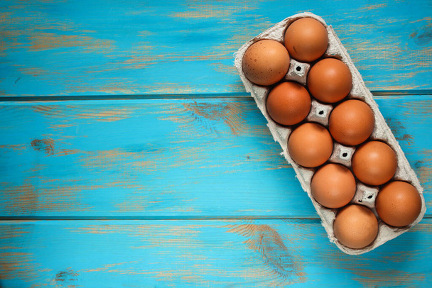 eggs in a box on a blue wooden background. top view. free space for text.  - Foto, imagen