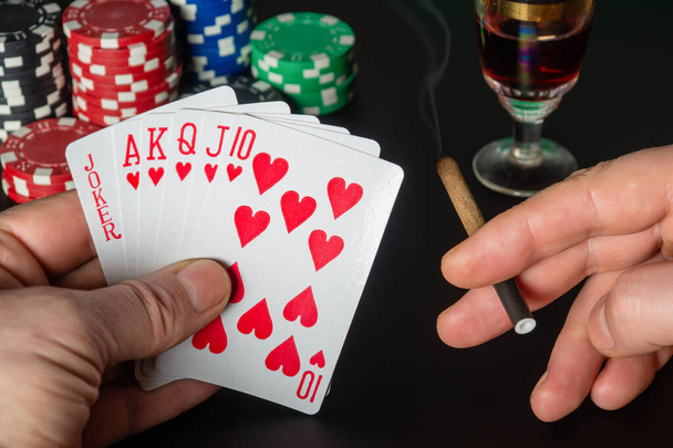 Cartes de poker avec cinq d'une combinaison aimable. Gros plan d'une main de joueur tient des cartes à jouer et sagaret dans le club de poker - Photo, image