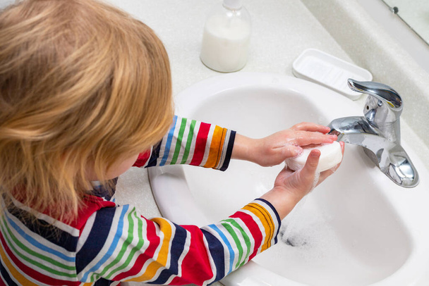 Küçük çocuk banyoda ellerini sabunla yıkıyor. - Fotoğraf, Görsel