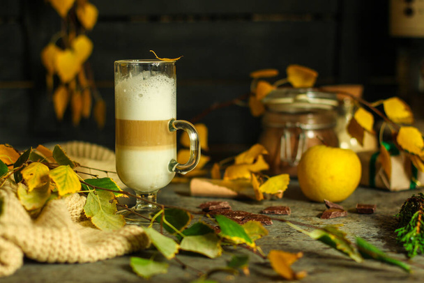 close up transparent cup of latte on autumn leaves background - Foto, afbeelding
