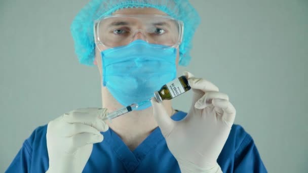 Travailleur de laboratoire médical en masque de gants de protection prêt à introduire une ampoule ou une bouteille avec vaccin anti-coronavirus moderna dans un laboratoire bactériologique - Séquence, vidéo