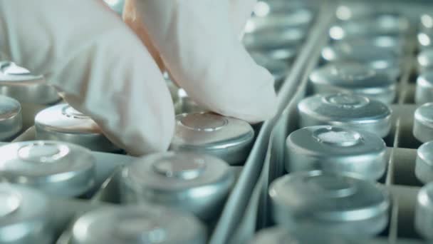 Рука медицинского работника в защитных перчатках взять флаконы или бутылки с антикоронавирусной вакцины из коробки, новые лекарства разрабатываются - Кадры, видео
