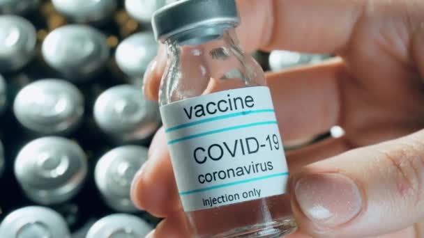 Vacuna del coronavirus de la mano de la mujer en frasco sobre fármacos farmacológicos en viales de fondo contra pandemia mundial - Metraje, vídeo