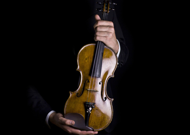 Hermosas manos masculinas sosteniendo un hermoso violín pulido en la oscuridad
 - Foto, imagen