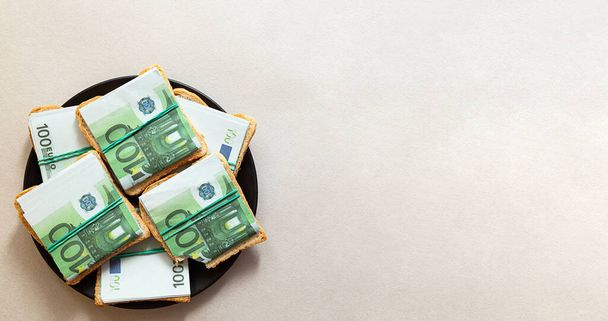 Creatieve minimalistische samenstelling - een bord sandwiches gemaakt van 100 eurobiljetten. Bewust consumptieconcept, duurzame levensstijl. - Foto, afbeelding
