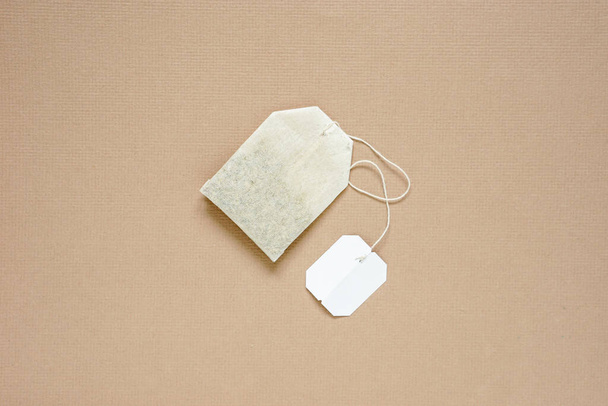 top view of dried tea bag with blank white paper tag placed on brown paper, copy space concept. - Valokuva, kuva