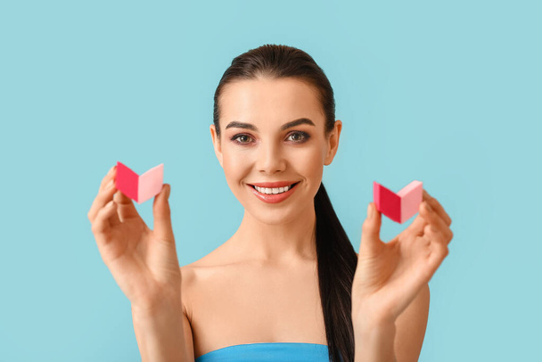 Mooie jonge vrouw met make-up sponzen op kleur achtergrond - Foto, afbeelding