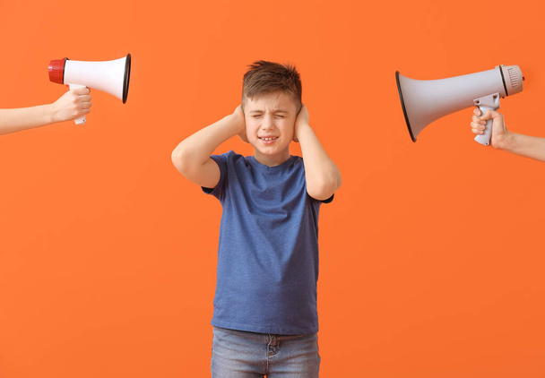 Handen met megafoons en kleine jongen die lijden aan luid lawaai op kleur achtergrond - Foto, afbeelding