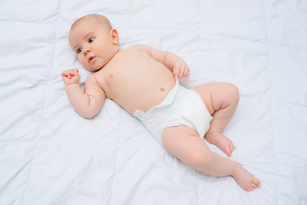 baby boy in a diaper lying on a crib on a white background. - Foto, afbeelding