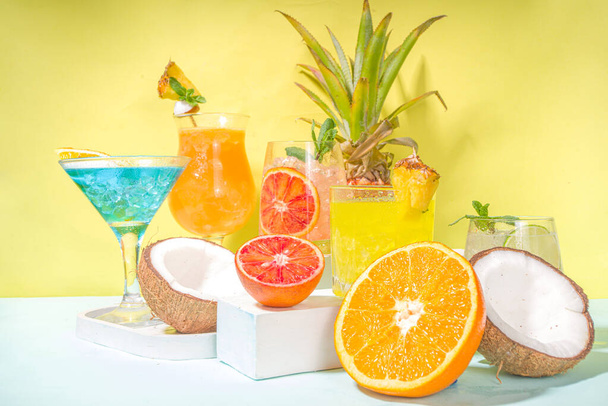 Kleurrijke zomer drankjes set. Diverse heldere alcohol cocktails en dranken, in verschillende glazen, met tropisch fruit op moderne heldere achtergrond kopieerruimte - Foto, afbeelding