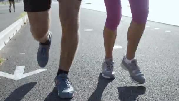 Male and female legs running on asphalt road - Footage, Video