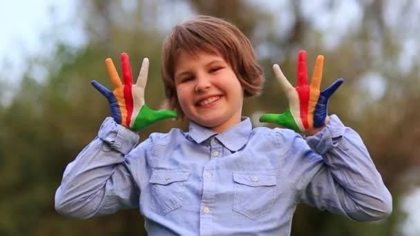 O miúdo joga às mãos do arco-íris. Menina criança alegre mostrar Olá gesto com as mãos pintadas em cores bandeira Seychelles.  - Filmagem, Vídeo