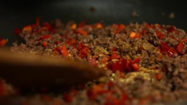 Přidání mexické směsi koření k mletému hovězímu a červené papriky vařené na pánvi na smažení. Míchání s dřevěnou špachtlí. Proces výroby quesadillas - Záběry, video