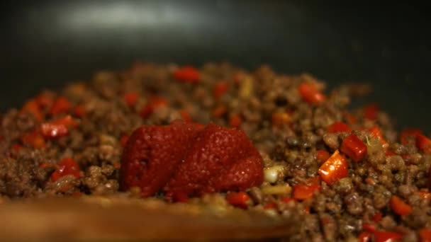 Додавання томатної пасти та води до меленої яловичини та червоного болгарського перцю, що готується на сковороді. Змішування з дерев'яним шпателем. Процес виготовлення квазаділлів
 - Кадри, відео