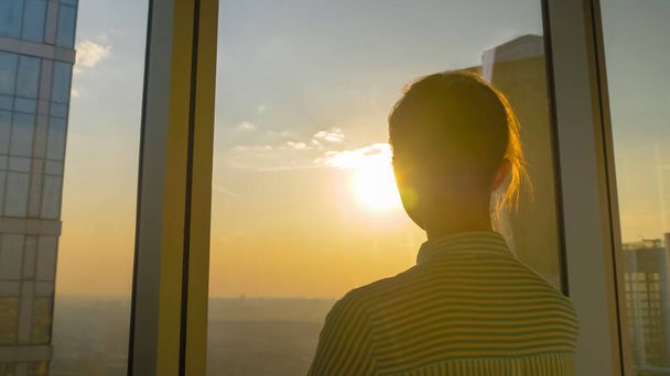 Takaisin näkymä nainen katselee kaupunkikuva kautta lasi-ikkuna pilvenpiirtäjä - Valokuva, kuva
