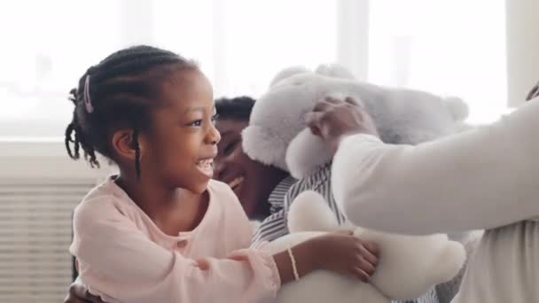 Afro-Amerikan ailesi, oyuncak ayıyla evindeki kanepede birlikte gülüp oynuyorlar. Genç anne, siyah kadın, ablası, küçük kızı, kızı ve tanınmaz halde olan babası içeride eğleniyor. - Video, Çekim