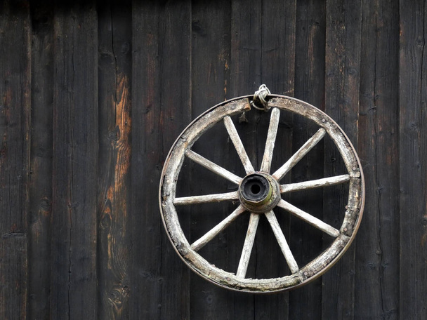 Rueda de un carro viejo en la pared de la casa antigua - Foto, Imagen