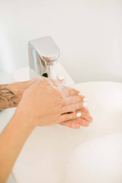 Kobieta myje ręce pod bieżącą wodą w łazience. Pranie rąk. Higiena rąk. Ochrona i zapobieganie pandemii koronawirusów.  - Zdjęcie, obraz