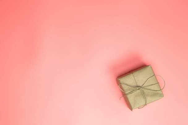Coffret cadeau enveloppé dans du papier brun, coffret cadeau avec rose sur fond rose avec vue panoramique sur l'espace de copie, Fête des mères, Saint-Valentin, concept d'anniversaire. Design moderne - Photo, image