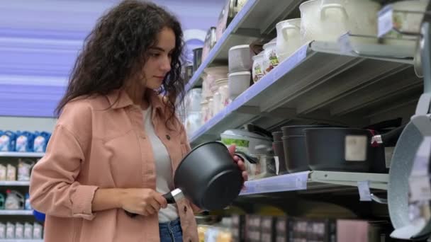 Cliente femminile che sceglie una casseruola nell'ipermercato - Filmati, video