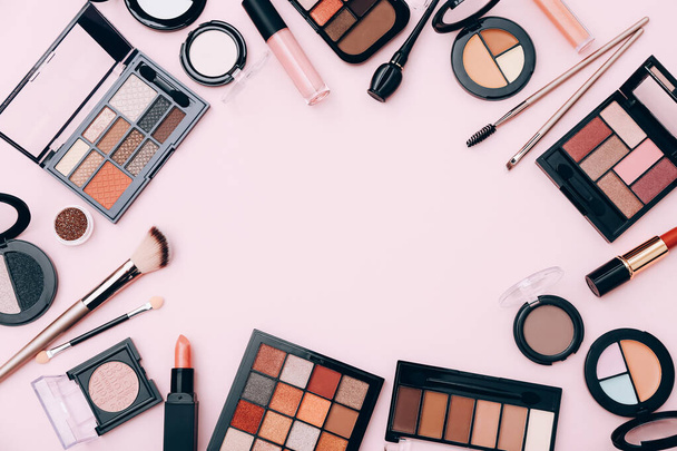 Make-up producten verspreid over roze achtergrond, bovenaanzicht - Foto, afbeelding