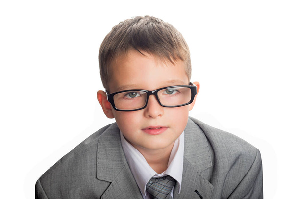 ビジネスマンのスーツと眼鏡でかわいい学童の肖像画は、白に隔離された。ビジネススーツのハンサムな子供. - 写真・画像
