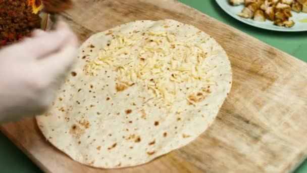 Tortilla mąka wypełniona tartym serem, mieloną wołowiną i warzywami. Proces produkcji meksykańskich quesadilli z mięsem wołowym, serem i warzywami - Materiał filmowy, wideo