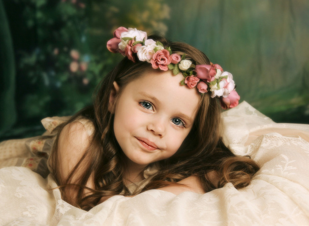 Élégant portrait d'une belle petite fille avec un halo de fleurs roses couché sur de la dentelle crème
 - Photo, image