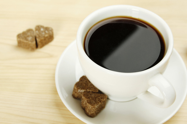 Closeup of a white cup of coffee next to lay pieces of sugar - Photo, image