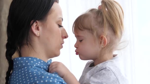 A little girl kisses her beloved mother, mom holds the child in her arms and hugs, the concept of a happy family life, the nanny calms the child, the parent is next to the kid together, 4K, close-up - Footage, Video