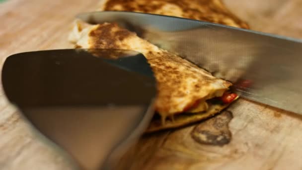 Κόβοντας ένα φρεσκοτηγανισμένο κοτόπουλο quesadilla σε ένα ξύλινο ξύλο κοπής. Διαδικασία παρασκευής μεξικανικών quesadillas - Πλάνα, βίντεο