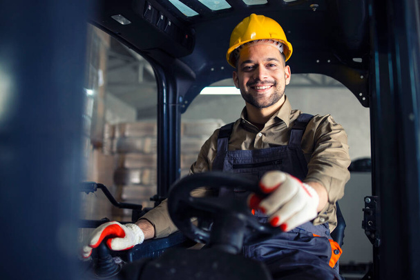 Портрет усміхненого кавказького оператора навантажувача, що керує машиною і працює на складі
. - Фото, зображення