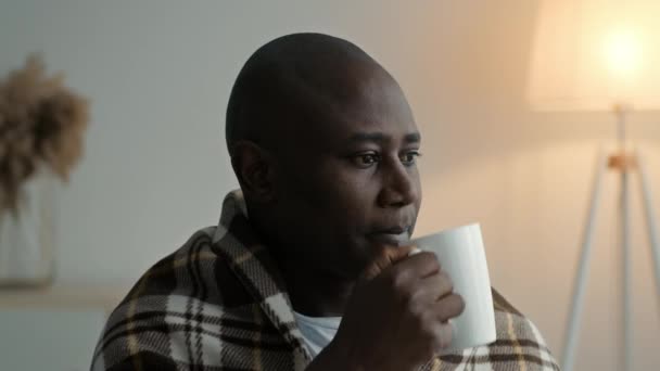 Malade homme noir boire du thé chaud ayant la fièvre à la maison - Séquence, vidéo