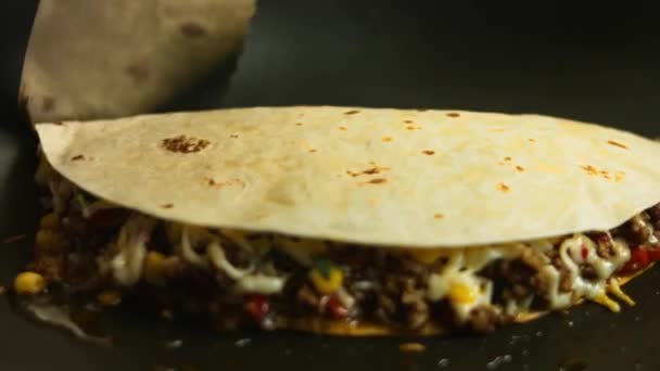 Frying a freshly wraped beef quesadilla on a frying pan. Turning over and covering the quesadilla. Process of making mexican quesadillas - Footage, Video
