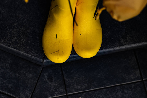 A pair of yellow rubber boots outside after rain on a gray background. - Photo, Image