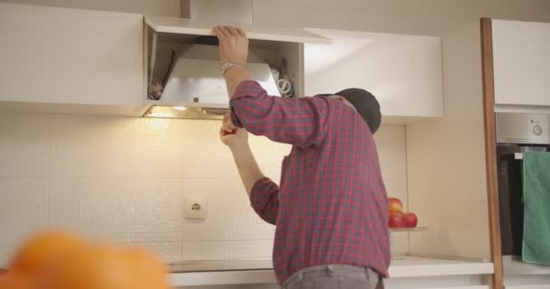 Handyman con un cinturón de herramientas que fija los respiraderos de aire de la cocina - Metraje, vídeo