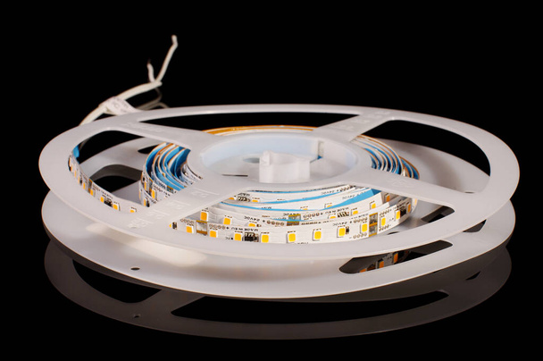 Flexible light emitting diode LED strip in the reel isolated on the black reflective background - Photo, Image