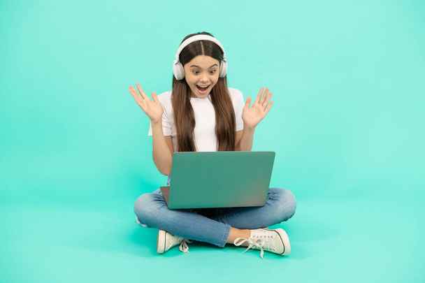 sorprendida chica adolescente utilizar portátil inalámbrico para videollamada o escuchar webinar en los auriculares, comprar en línea. - Foto, imagen