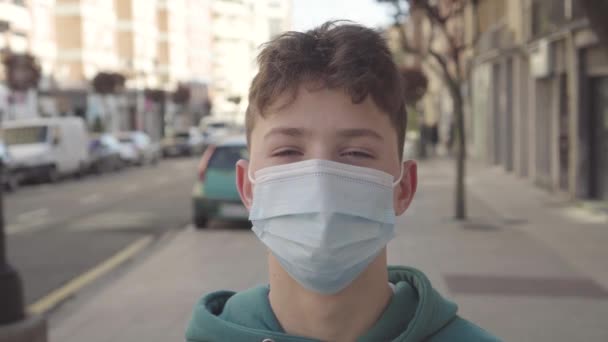 Un adolescent ouvre les yeux alors qu'il se tient debout dans un masque jetable de protection médicale dans une rue de la ville avec une route. Gros plan portrait - Séquence, vidéo