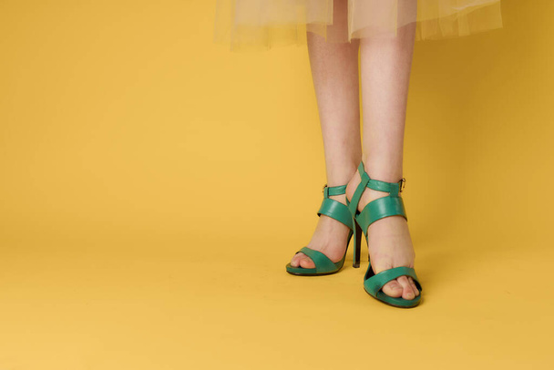 Γυναικεία πόδια πράσινα παπούτσια κομψό τρόπο ζωής κίτρινο φόντο - Φωτογραφία, εικόνα