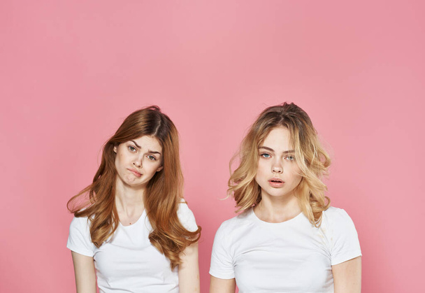 Tシャツを着た2人の女性ファッショングラマーコミュニケーション感情ピンクの背景 - 写真・画像