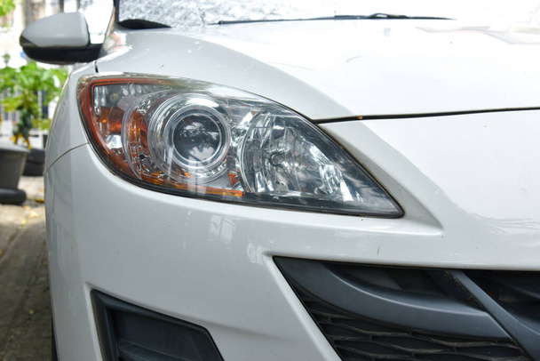 stara i niewyraźna powierzchnia reflektora spowodowana warunkami pogodowymi i starzeniem się białego samochodu - Zdjęcie, obraz