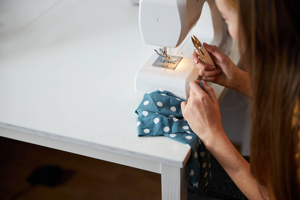Женщина использует современную швейную машинку в мастерской - Фото, изображение