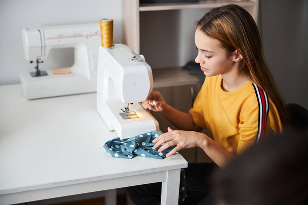 Cute dziewczyna krawcowa szycie tkaniny w warsztacie - Zdjęcie, obraz