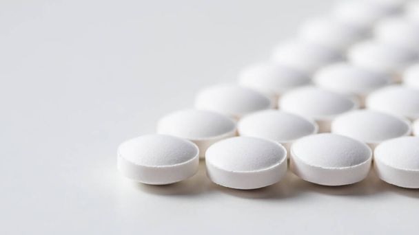 Linhas de comprimidos no fundo branco. Conceito de saúde, medicina, farmácia e doença - Foto, Imagem